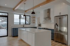 a kitchen with an island and stainless steel refrigerator freezer next to a sliding glass door