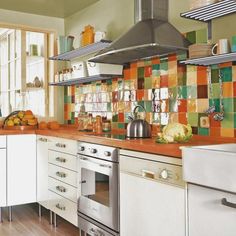 a kitchen with white cabinets and colorful tiles on the backsplash