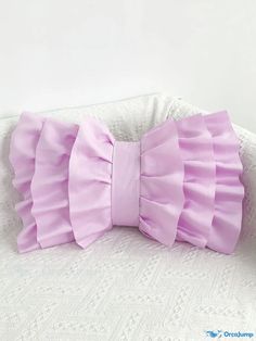 a purple bow on top of a white pillow