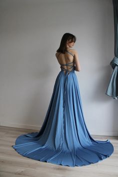 a woman in a blue dress is looking at something off to the side with her back turned