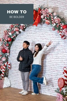 a man and woman standing in front of a wall with candy canes