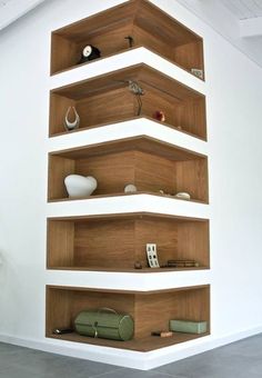 an empty room with wooden shelves on the wall and vases on the floor in front of it