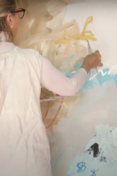 a woman is painting on the wall with white paint