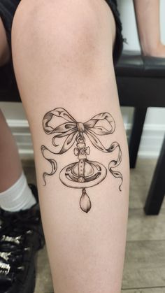 a woman's leg with a tattoo on it that has a bow and bells