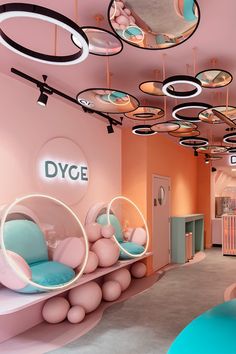 the interior of a children's playroom with pink walls and circular mirrors hanging from the ceiling