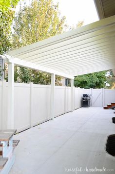 an outdoor patio area with white walls and wooden benches