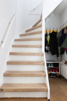 there is a set of stairs leading up to the second floor in this closet with clothes on hangers