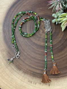 This gorgeous necklace with two tassels is designed with a unique look. It is made from a mix of czech glass beads in different shades of green and shapes. In between the purple beads are brown agate beads for a beautiful contrast. All metal components are silver plated. The pendant connector is vintage inspired rectangle shape that is about 1.25 inches long. The entire length of the pendant with tassels is 6.25 inches long. This necklace is similiar to a lariat style. The necklace length is 27. Thinks To Make With Old Beaded Necklaces, Cheap Beaded Metal Long Necklace, Neaded Necklace With Tassels, Cheap Dangling Beads Necklaces As Gifts, Cheap Metal Beaded Long Necklace, Cheap Traditional Long Beaded Necklaces, Cheap Green Necklaces With Wooden Beads, Cheap Green Beaded Pendant Necklaces, Cheap Green Beaded Pendant Necklace