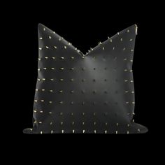 a black pillow with gold studding on the front and back of it, against a black background