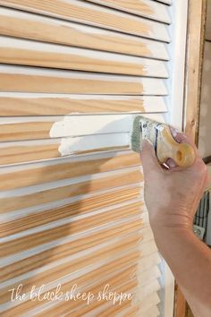 a person painting the side of a window with white paint