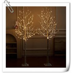 two lighted trees in the shape of branches with no leaves on them, are standing next to each other