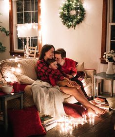 a man and woman sitting on a couch with christmas lights