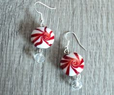 two red and white lollipop earrings on wooden table