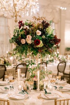 an elegant centerpiece with greenery and flowers sits atop a table in the ballroom