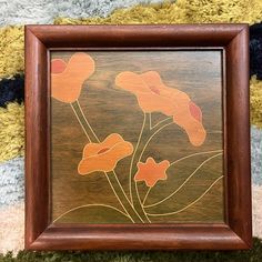 a wooden frame with some flowers painted on it's side in brown and orange