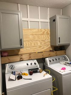 a washer and dryer in a small room with unfinished wood on the wall