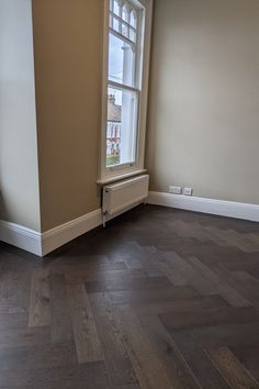 an empty room with hard wood flooring and a radiator in the corner