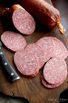 several slices of salami on a cutting board with a knife