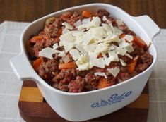 a casserole dish with meat and cheese in it on a wooden board, ready to be eaten