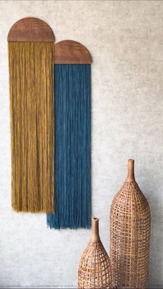 two vases sitting next to each other on top of a table near a wall