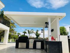 an outdoor kitchen with grills and cabinets under a covered area in front of a house