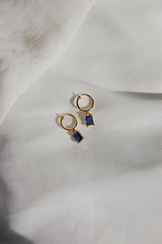 These dainty earrings are made with sapphire rhinestone charms and 18 karat gold plated huggie hoops. This gold plating protects against wear and tear, tarnishing, and light contact with substances such as water. Closures: * Standard gold hoops are hypoallergenic and nickel free (18 karat gold plated). * Clip on gold hoops are hypoallergenic and nickel free (18 karat gold plated). How to wear clip ons: Hold the earring in one hand while pulling the closure open with the other hand, place the ear Blue Small Hoop Huggie Earrings, Blue Hypoallergenic Small Hoop Jewelry, Hypoallergenic Blue Small Hoop Jewelry, Blue Hypoallergenic Small Hoop Huggie Earrings, Blue Hoop Huggie Earrings Gift, Hypoallergenic Blue Small Hoop Huggie Earrings, Blue Huggie Hoop Earrings For Pierced Ears, Blue Huggie Hoop Earrings For Gift, Blue Huggie Hoop Earrings As Gift