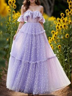 a woman wearing a purple dress standing in front of sunflowers