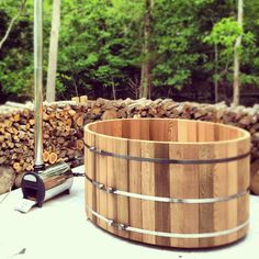 a large wooden barrel sitting on top of a table next to firewood stacked in the background