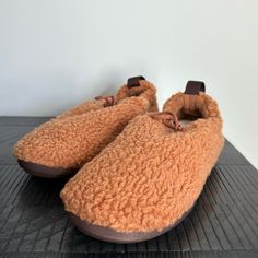 a pair of brown slippers sitting on top of a wooden table