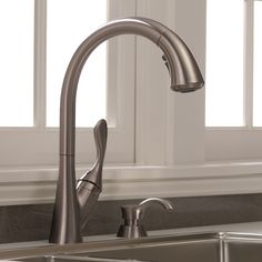 a stainless steel kitchen sink with faucet and soap dispenser