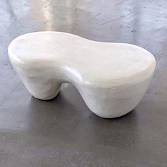 a white bench sitting on top of a cement floor