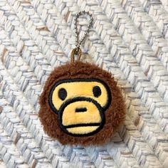 a monkey keychain hanging from a chain on top of a woven table cloth