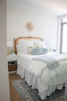 a bed with white linens and pillows in a bedroom next to a large window