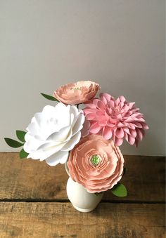 an arrangement of pink and white flowers in a vase on top of a wooden table