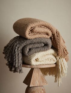 stack of blankets sitting on top of a wooden table next to a white and brown wall