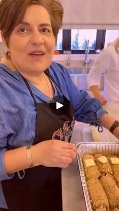 a woman in an apron holding a tray of food