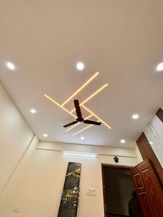 the ceiling fan is lit up in an empty room with white walls and wooden doors