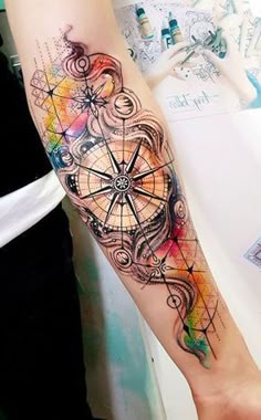 a person with a tattoo on their arm that has an image of a compass in it