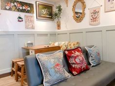 a couch with several pillows on top of it in a room filled with framed pictures