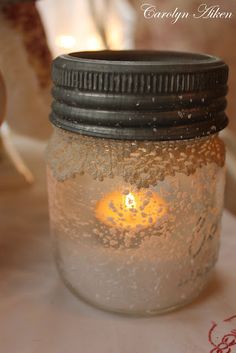 a lit candle in a mason jar on a table