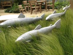 three metal fish sculptures sitting in the grass