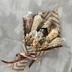 a box filled with different types of food on top of a table next to a brown ribbon