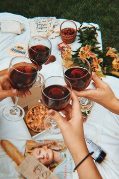 several people toasting with wine glasses on a picnic table outside in the grass and flowers