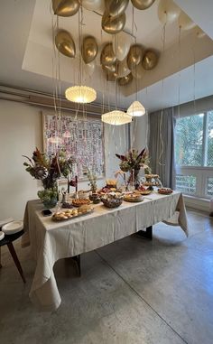 a table is set up with food and balloons hanging from the ceiling in front of it