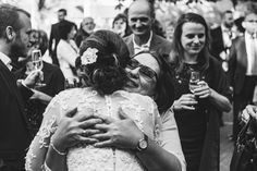 two women hugging each other in front of a group of people wearing suits and ties