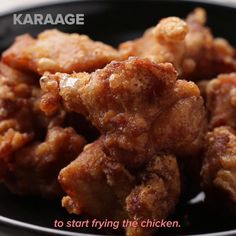 fried chicken on a black plate with the words karaage written in red above it