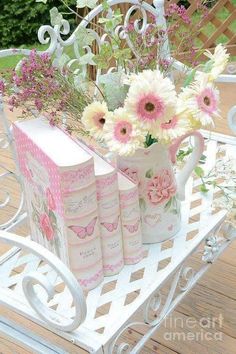 flowers and books are sitting on a bench with a book in the shape of a teapot