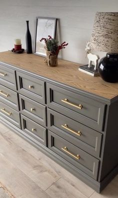 a grey dresser with gold handles and knobs in a room next to a lamp