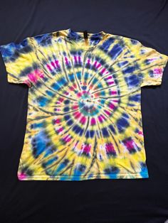 Etsy Each of my Tie Dye products is hand made by myself a small batch artist based in Colorado. All shirts start with a cotton shirt used for its great comfort over time and its ability to hold color. The use of Fabric reactive dye provides years of bright colors. Each shirt is a unique item and there are no two alike.  This XL shirt is made in a classic spiral design. With a good amount of yellow this shirt is bright and happy. Weather at the park, the beach, or the concert, this shirt is one t Artistic Multicolor Cotton Shirt, Artsy Multicolor Cotton T-shirt, Artistic Tie Dye Cotton Tops, Yellow Hippie Cotton Top, Artsy Cotton Summer Shirt, Artsy Cotton Shirt For Summer, Handmade Cotton Hippie Tops, Hand Dyed Yellow Cotton Tops, Casual Multicolor Handmade Tops