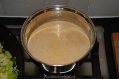 a pot on top of a stove filled with liquid and vegetables next to a skillet